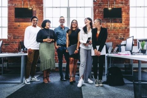 Mångsidigt team i varierad, avslappnad klädsel på ett kontor